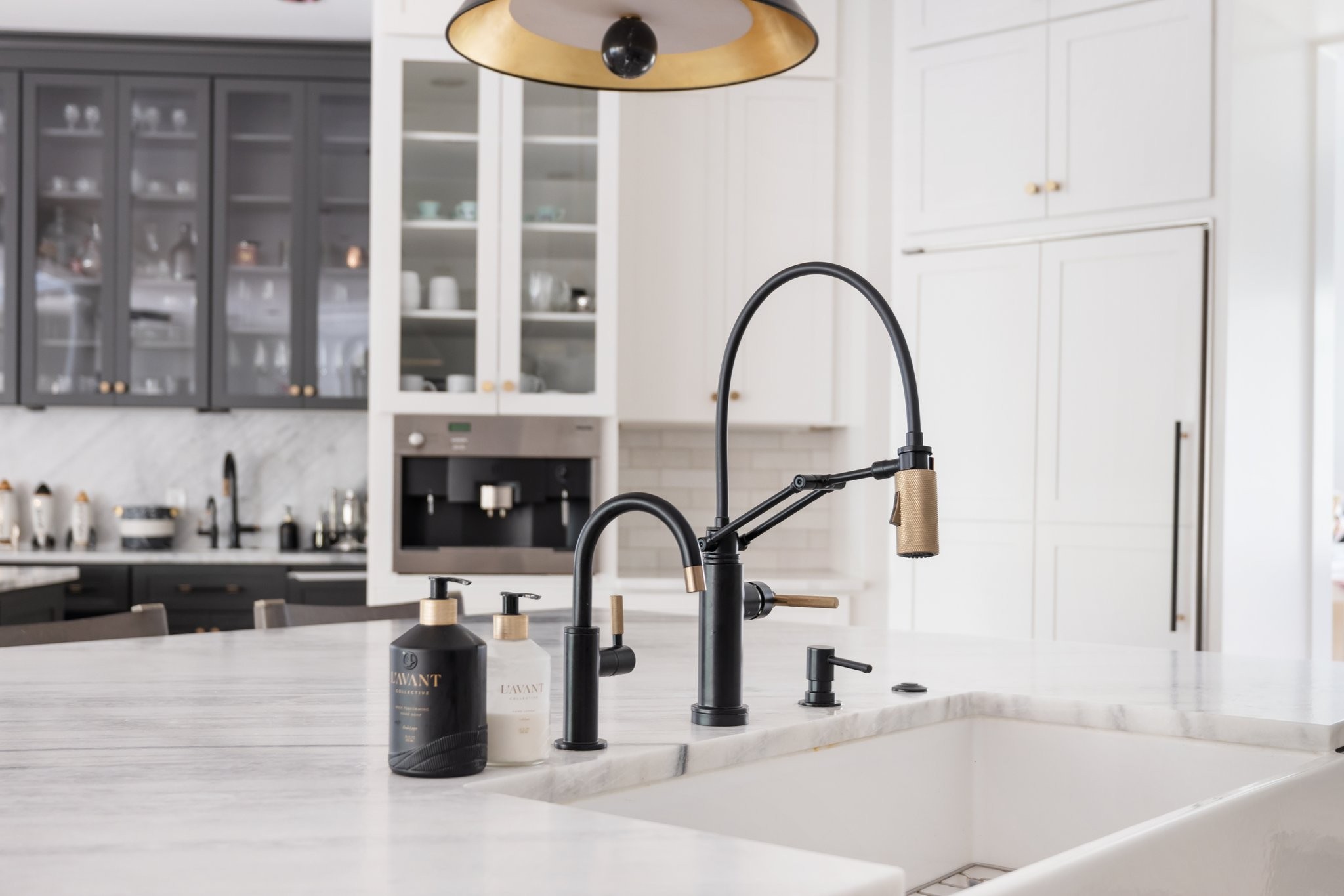 Kitchen sink with a black-and-brass faucet set into a white marble island.