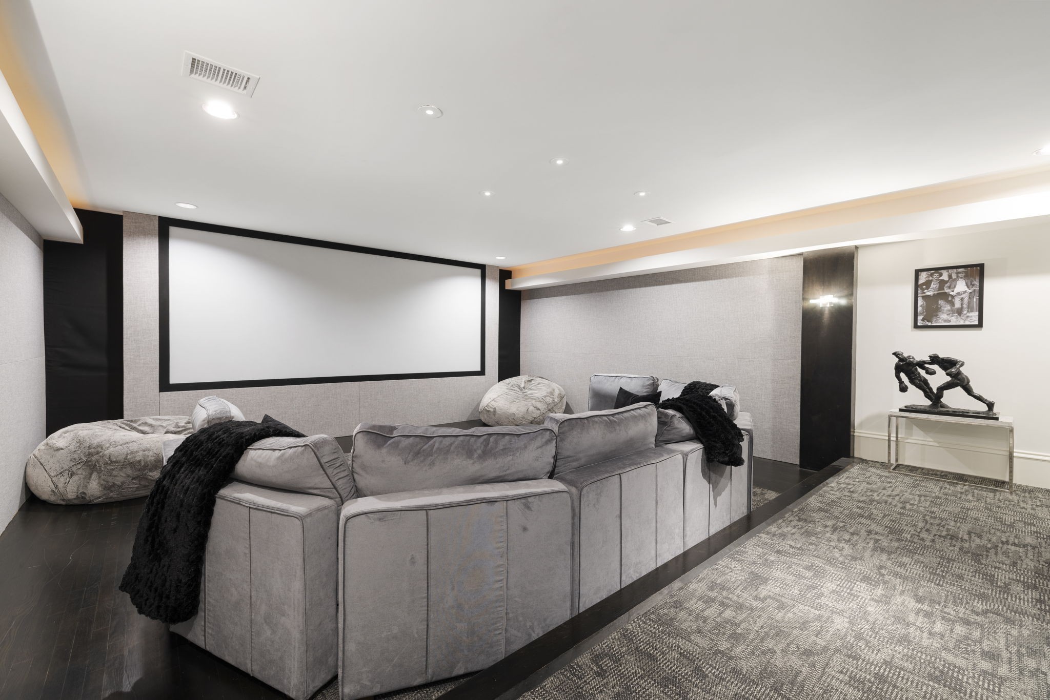 Home theater with a large projection screen and gray sectional seating.