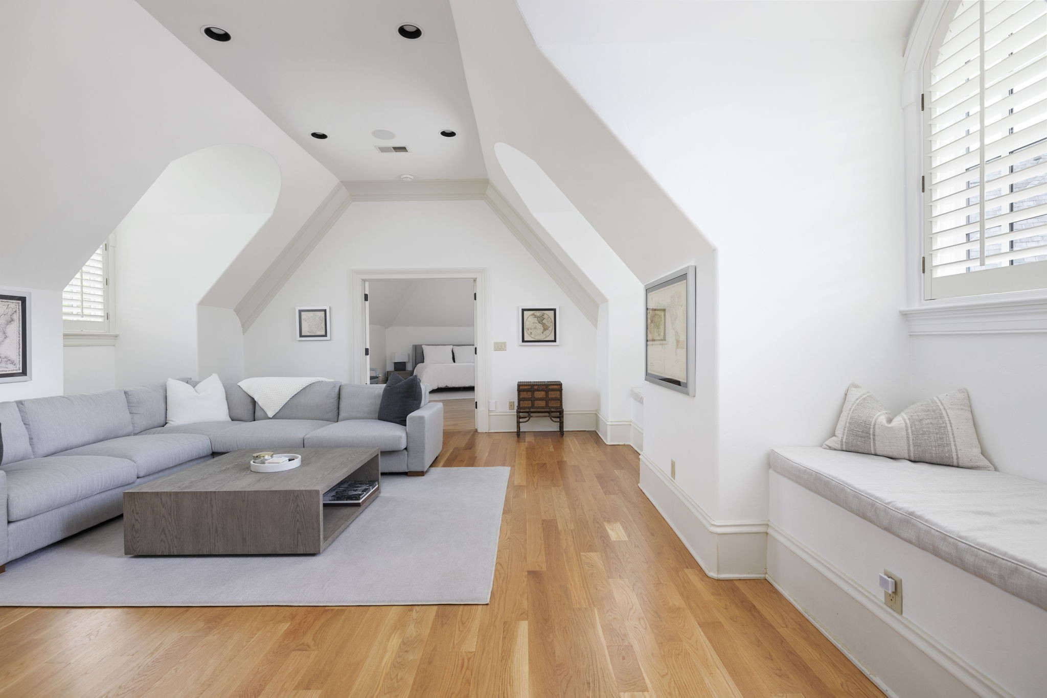 Upstairs sitting room with a gray sectional, vaulted ceiling, hardwood floors, and a built-in window bench.