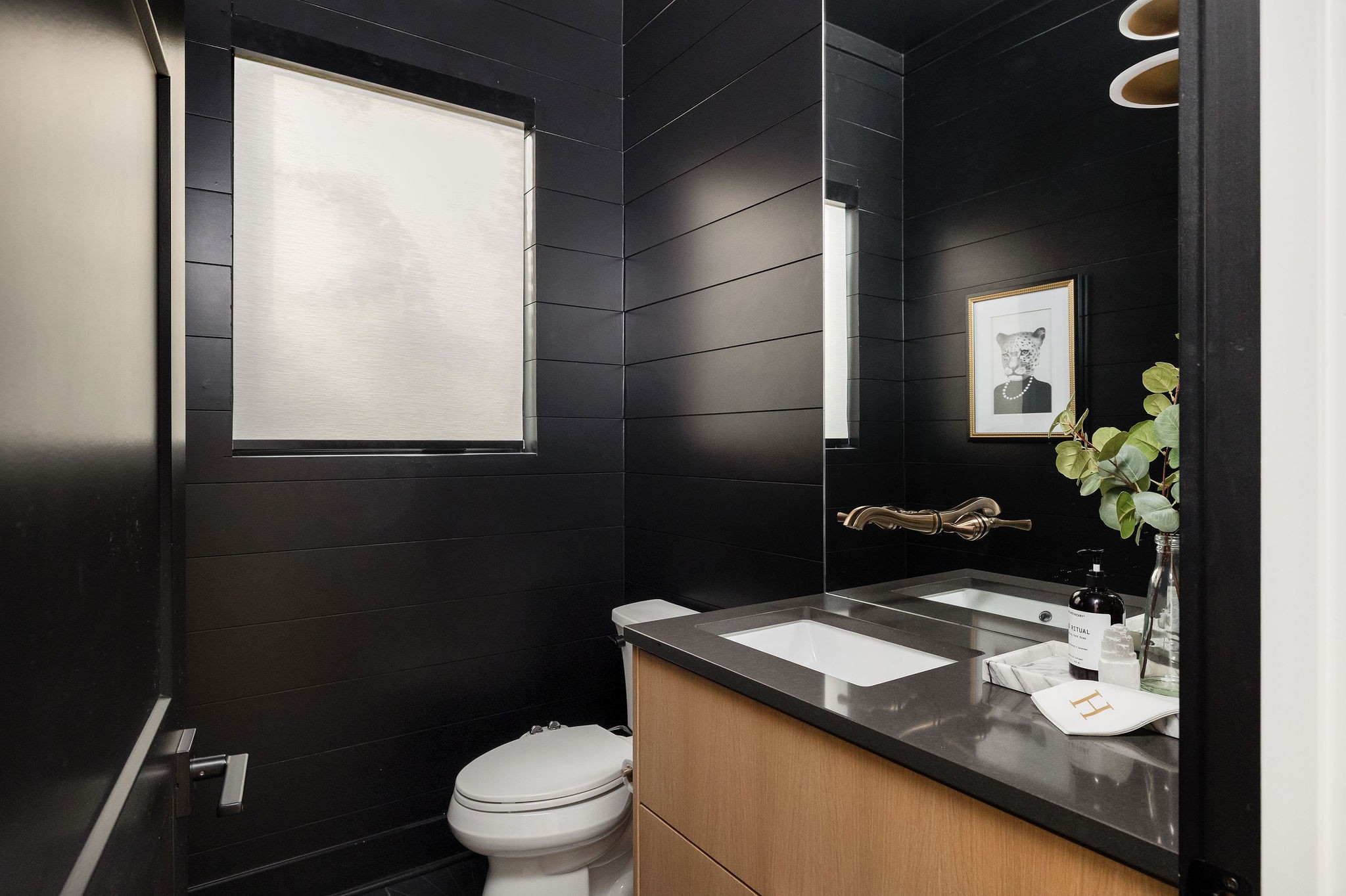 Modern bathroom with charcoal walls, wood vanity, white sink, and framed animal portrait.