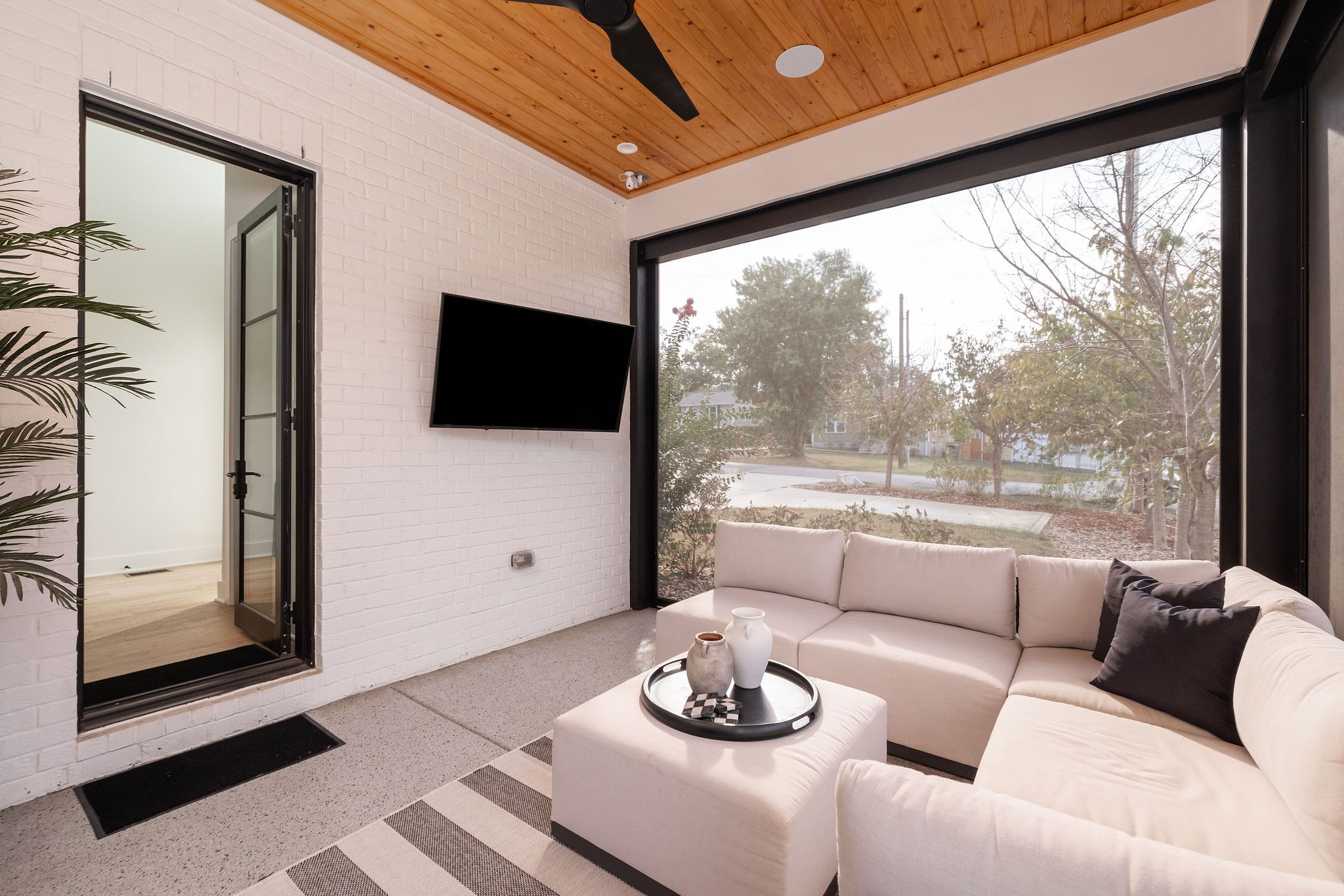 Living room with a white sectional, wood-plank ceiling, and large picture window overlooking the street.