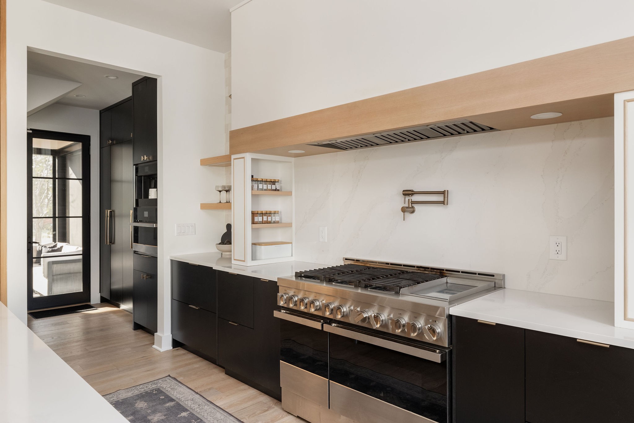 Modern kitchen with dark cabinetry, a wide stainless steel range, and a wood-accented hood.
