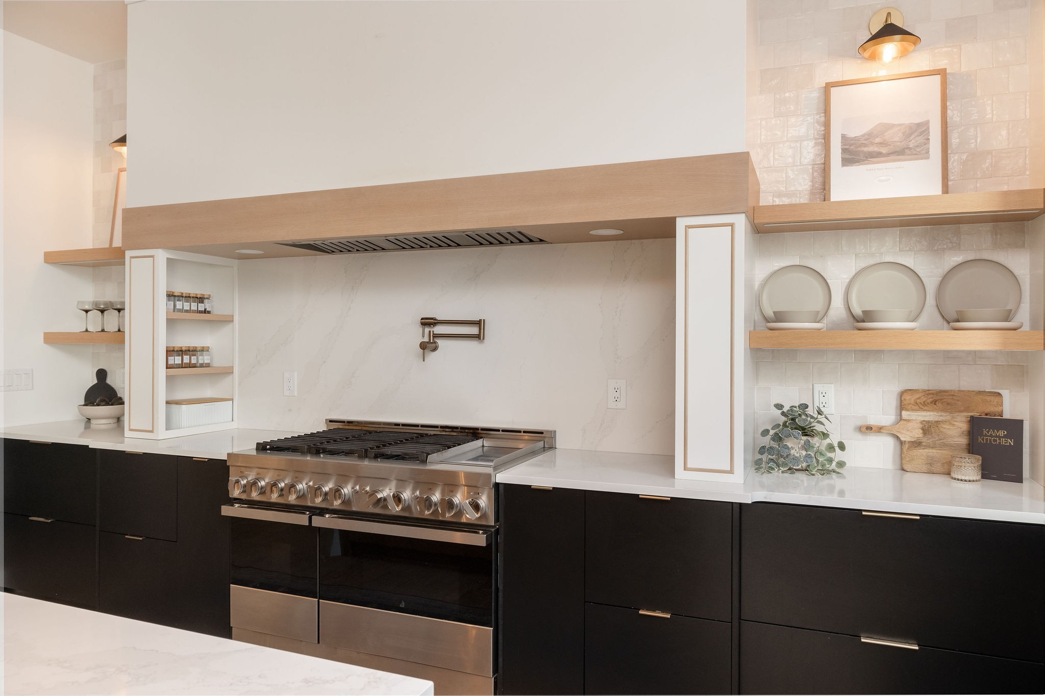 Modern kitchen with a stainless-steel range, dark cabinets, and open display shelves.