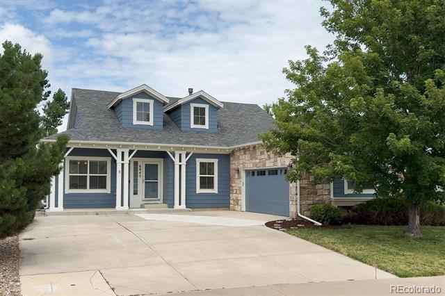 Blue two-story home with stone accents, roof dormers, an attached garage, and a broad concrete driveway.