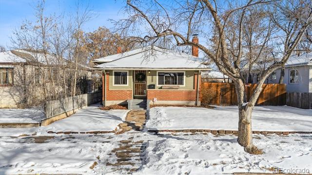 Single-story brick-and-siding house with a snowy yard and mature leafless trees.
