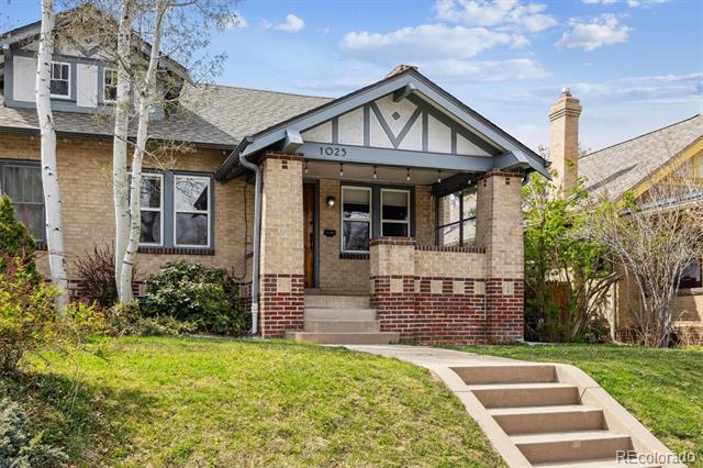 Brick house with a covered front porch, decorative gable, and concrete steps.