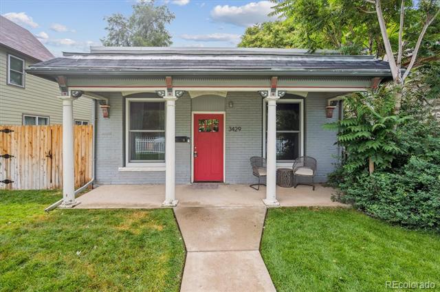 Gray brick house with a covered porch, white columns, and a red front door.