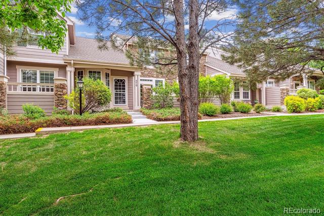 Residential building with landscaped front lawn, mature tree, and stone accents.