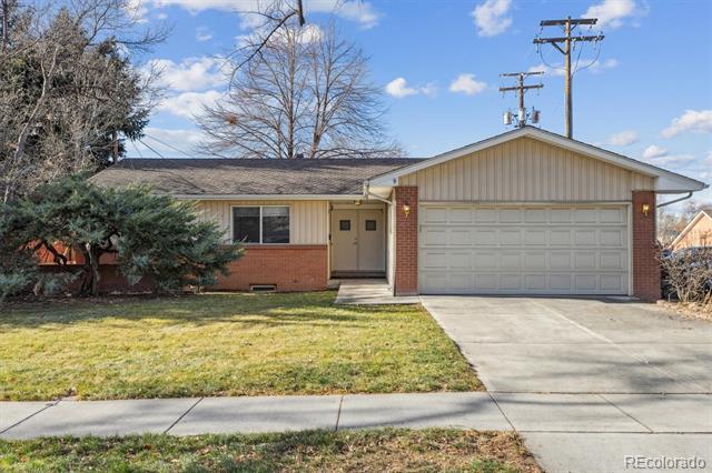 Single-story ranch home with tan siding, brick accents, and an attached two-car garage.