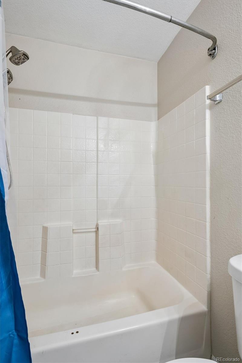 White bathtub and tiled shower with built-in shelves and a curved curtain rod.