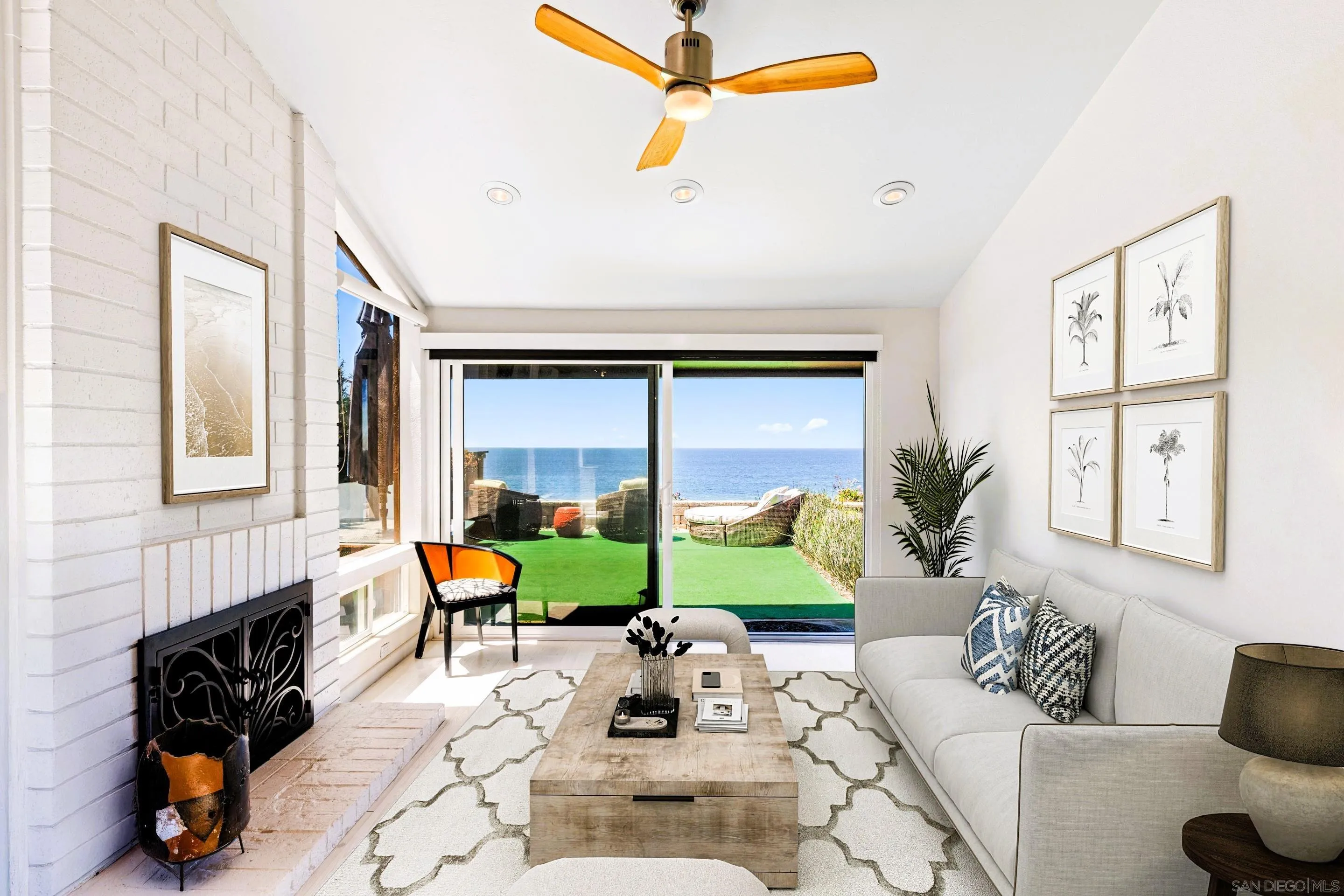 Bright oceanfront living room at 194 Neptune Ave in Encinitas, CA 92024-featuring ocean views, sliding glass doors, white brick fireplace, and serene indoor-outdoor flow