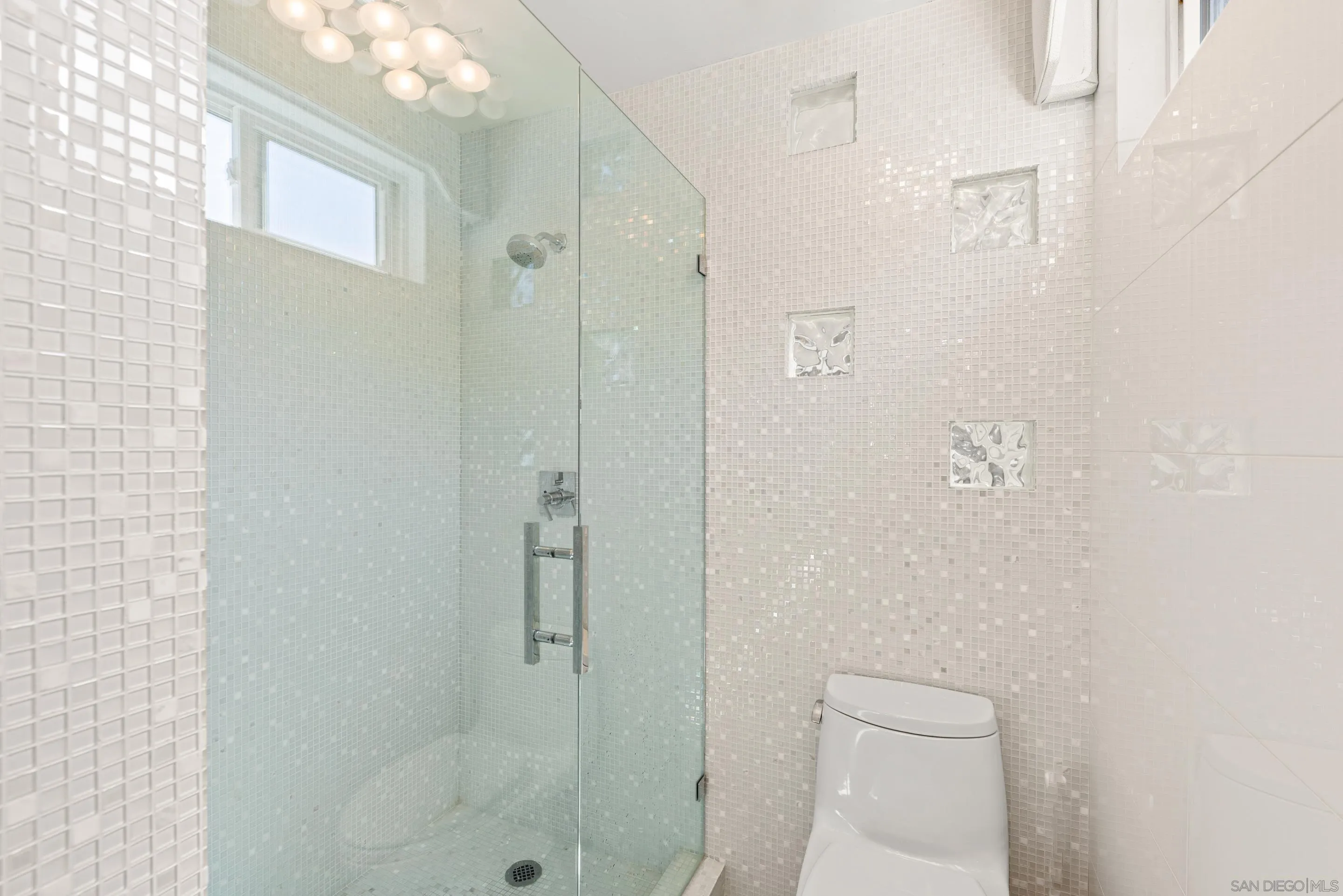 Primary bathroom at 194 Neptune Ave-Encinitas CA-92024-featuring glass-enclosed shower, mosaic tile walls, modern fixtures, and natural light in this oceanfront home listed by FW Property Group