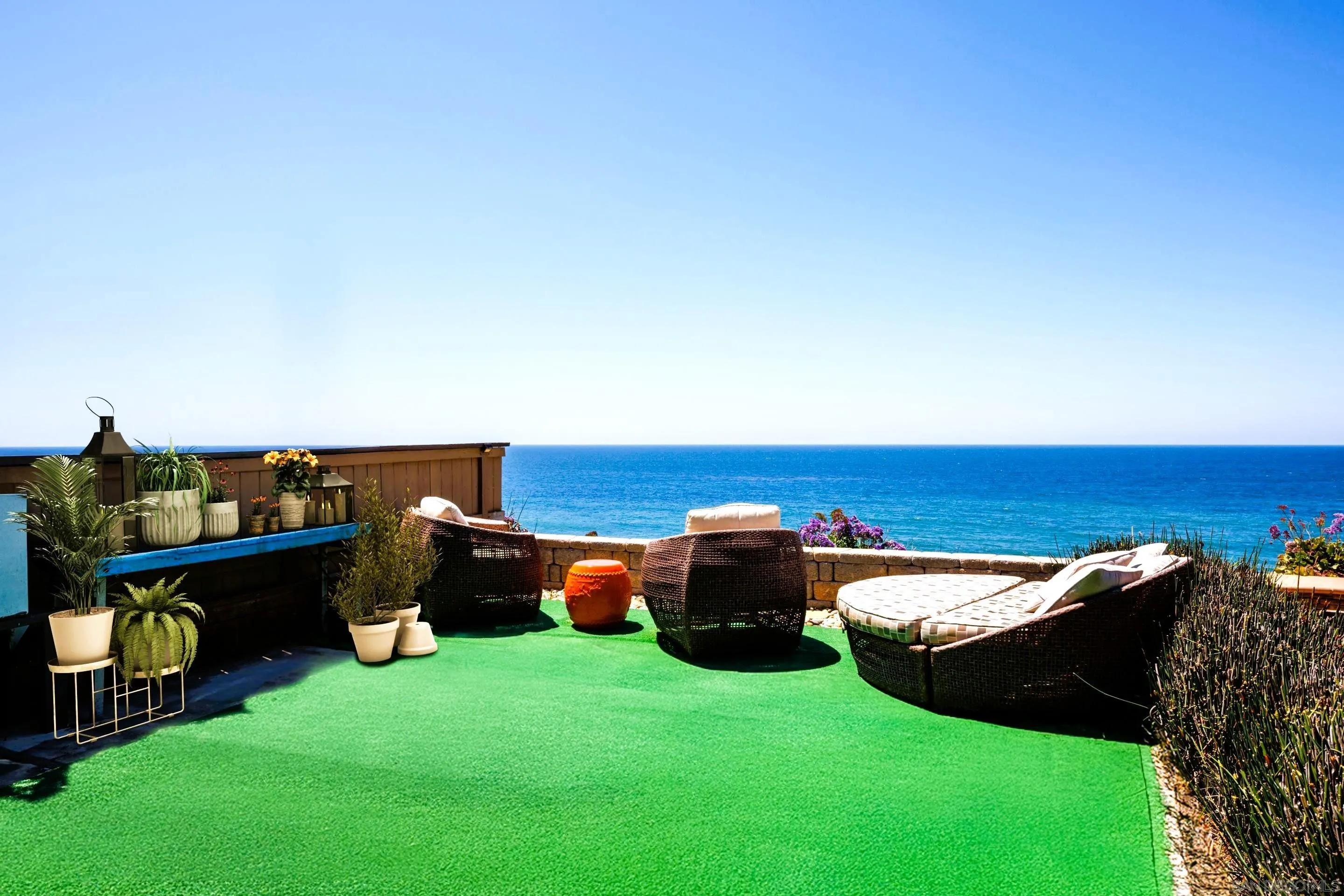 Stylish outdoor patio at 194 Neptune Ave-Encinitas-CA-92024—Leucadia-featuring wicker lounge seating, potted plants, turf flooring, and panoramic ocean views