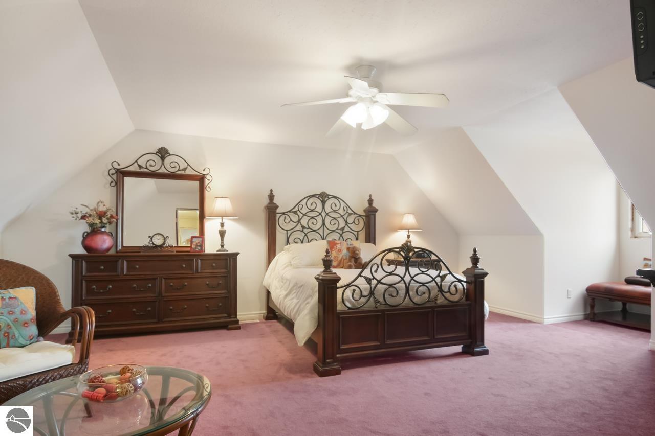 Furnished bedroom with an ornate metal-scroll bed, matching dresser, and pink carpet.