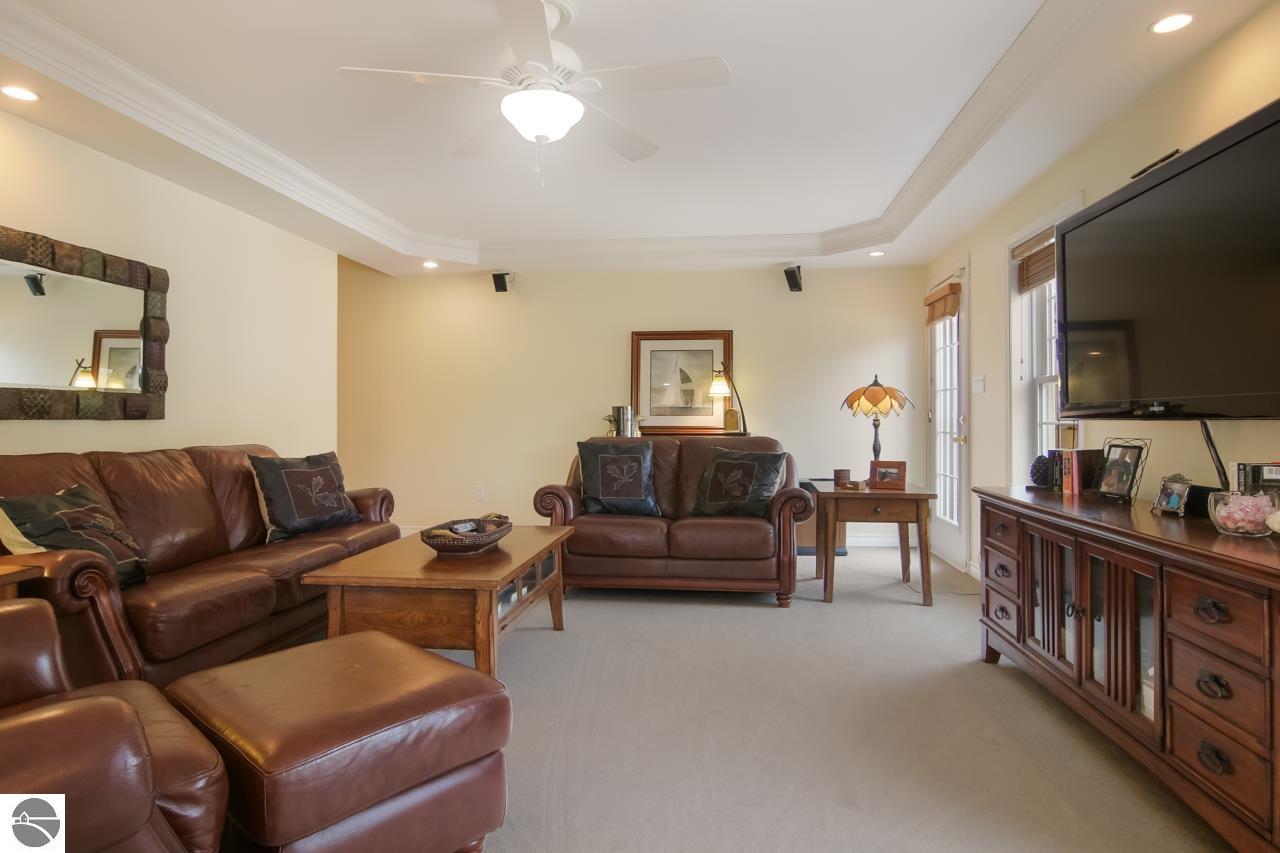 Furnished living room with brown leather seating, a wooden coffee table, and a large television.