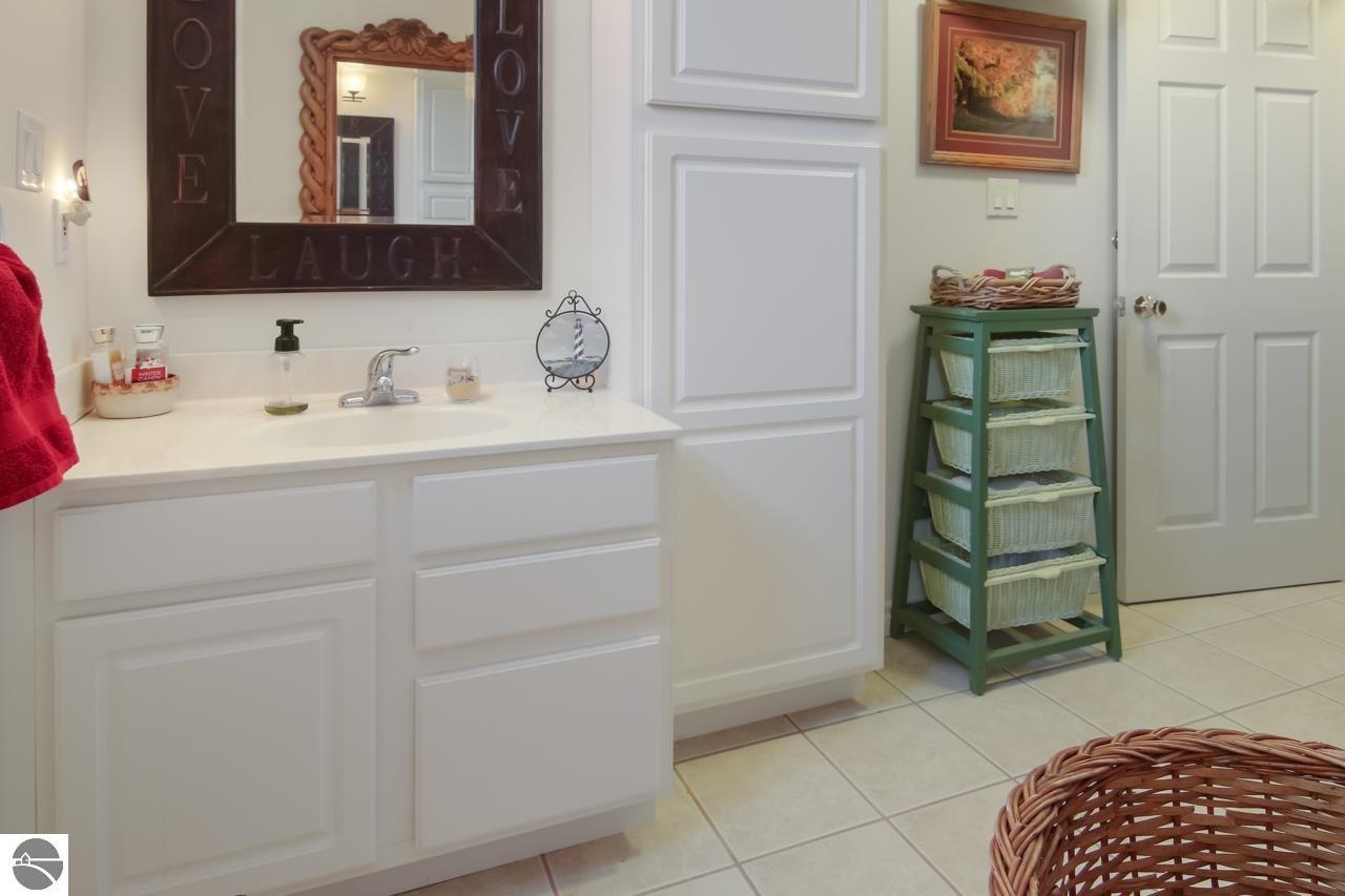 Bathroom vanity with an inscribed mirror and green basket stand beside the door.