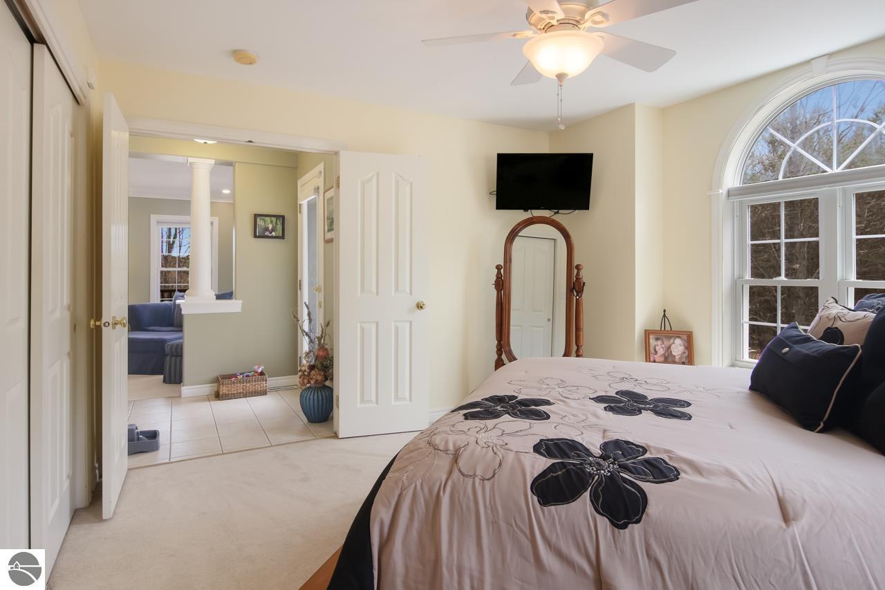 Bedroom with a floral comforter, arched window, and doorway to an adjoining sitting area.
