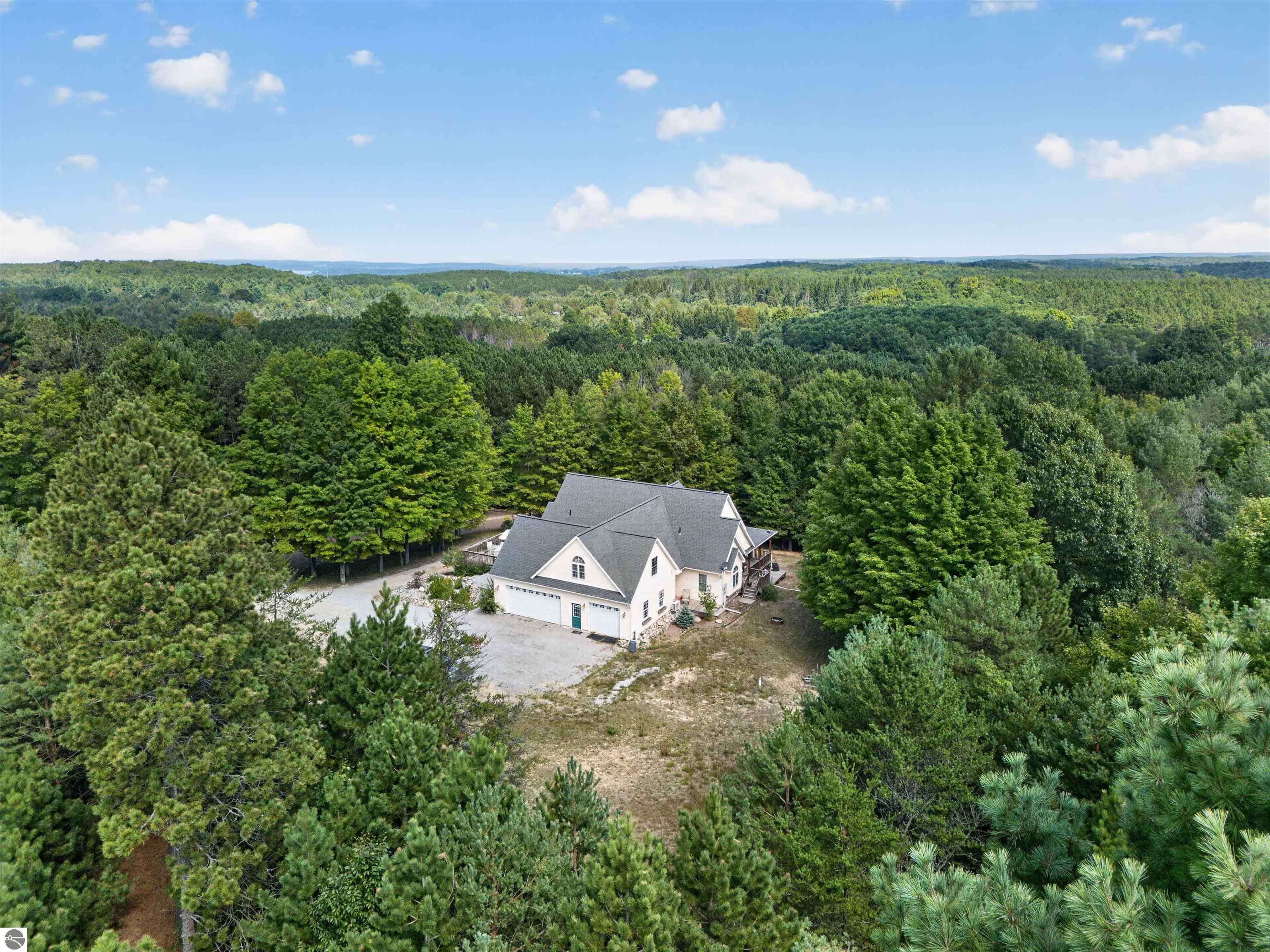 Aerial view of a gray-roofed house nestled among dense woodland.