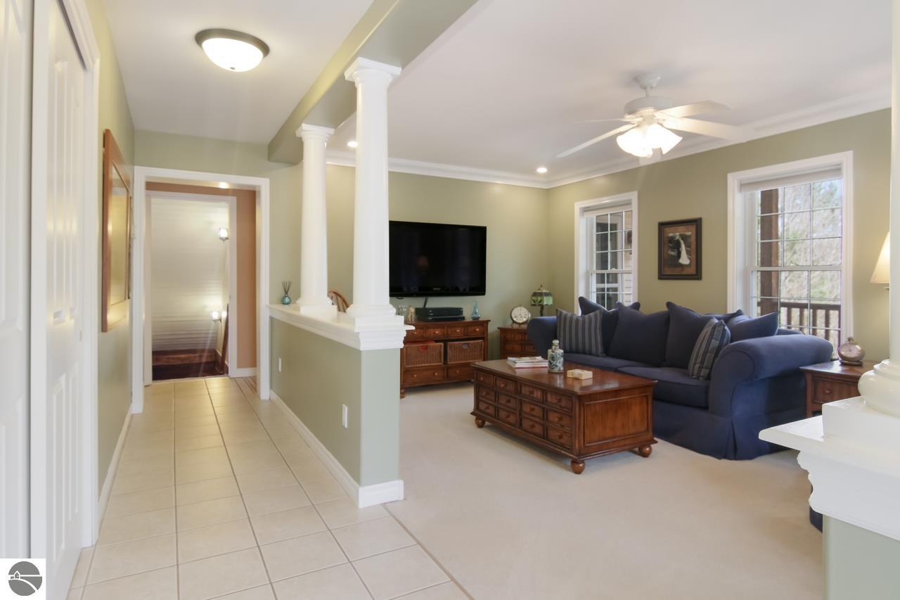 Furnished living room with a blue sofa, wooden coffee table, and tiled entry hallway.