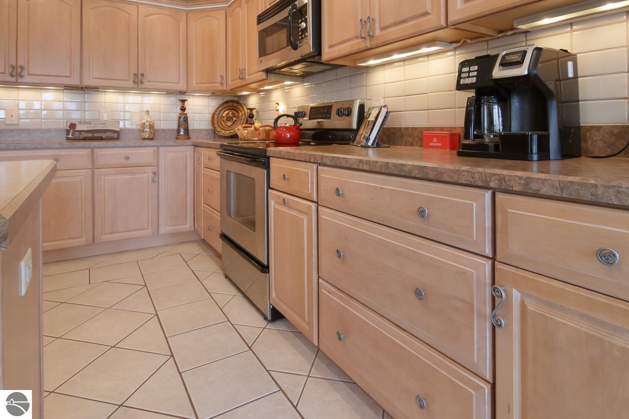 Kitchen with light wood cabinetry, tiled floors, and a stainless-steel range.