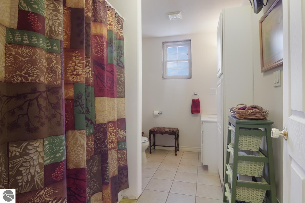 Bathroom with a colorful patchwork shower curtain and tiled floor.