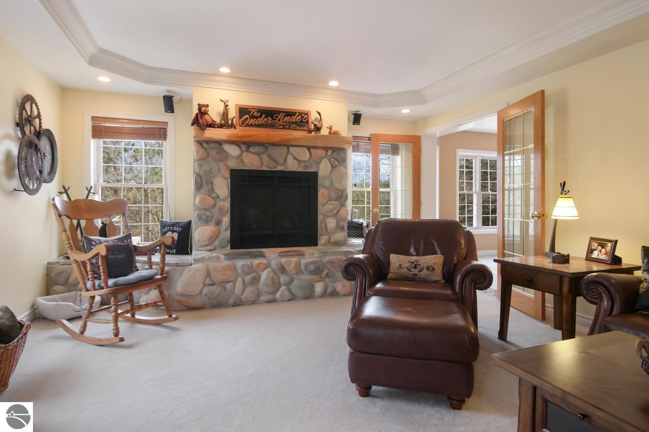 Living room with a stone fireplace, wooden rocking chair, and leather armchair with ottoman.
