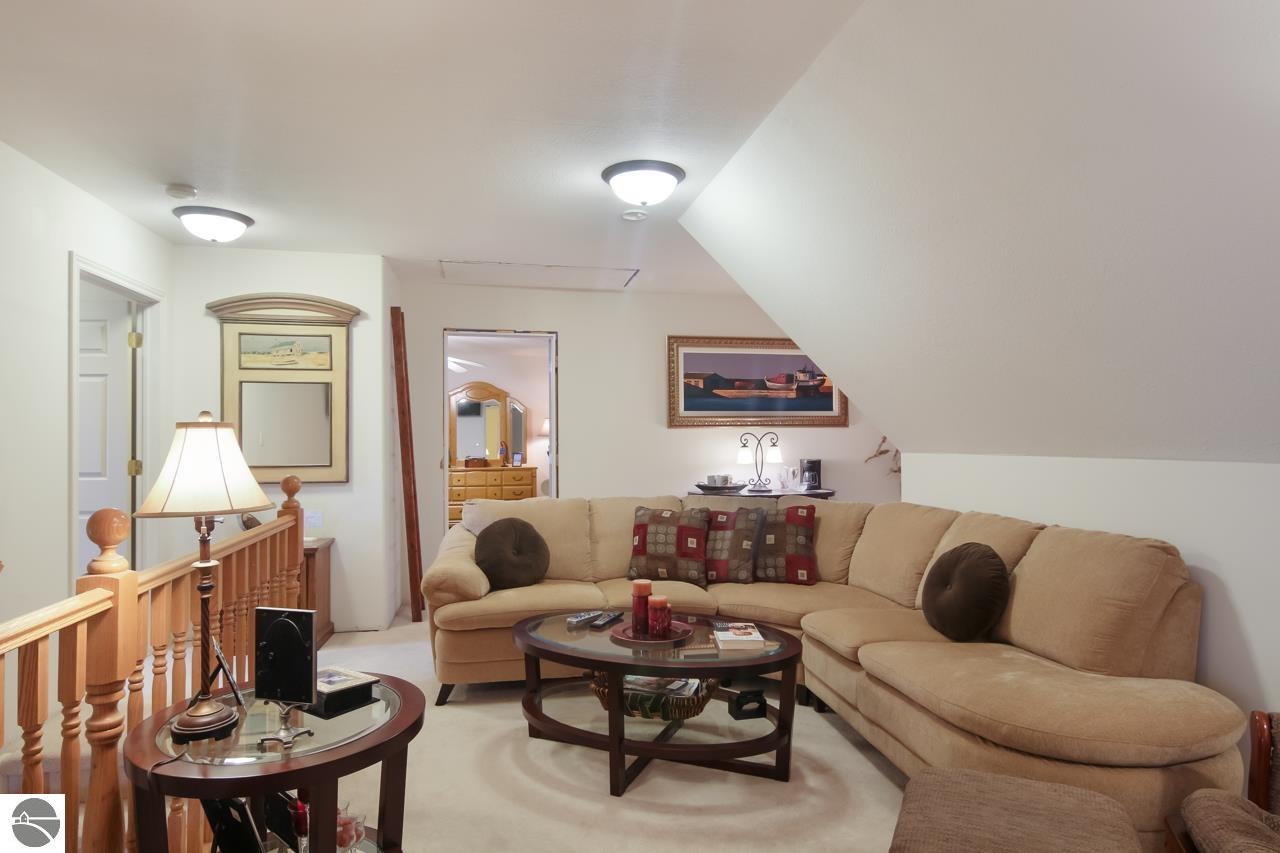 Furnished living room with a curved beige sectional, coffee tables, and a wooden stair railing.