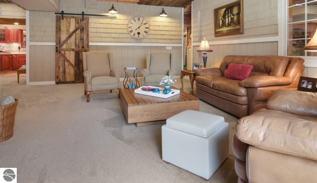 Furnished living room with a leather sofa, rustic sliding barn door, and large wall clock.