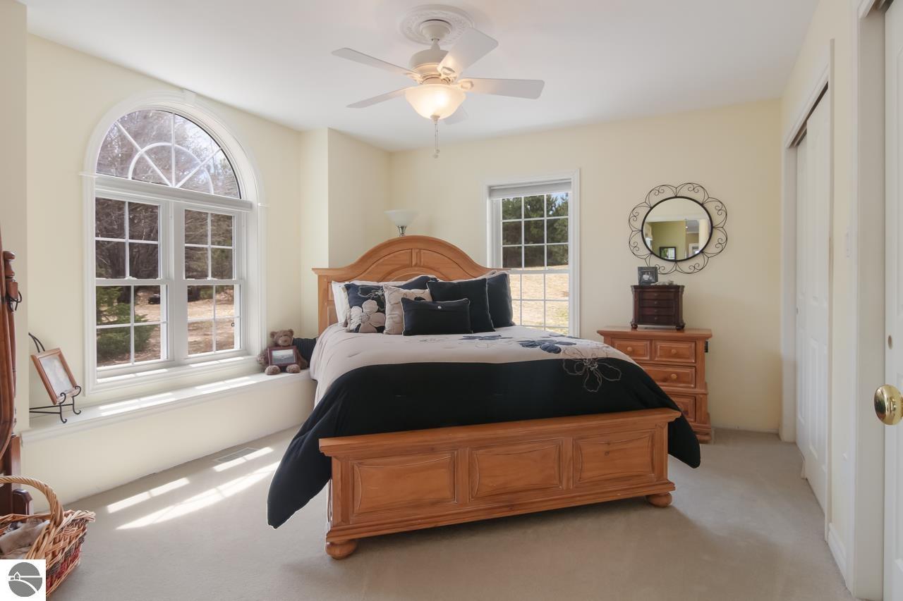 Furnished bedroom with a wooden bed, arched window, and ceiling fan.