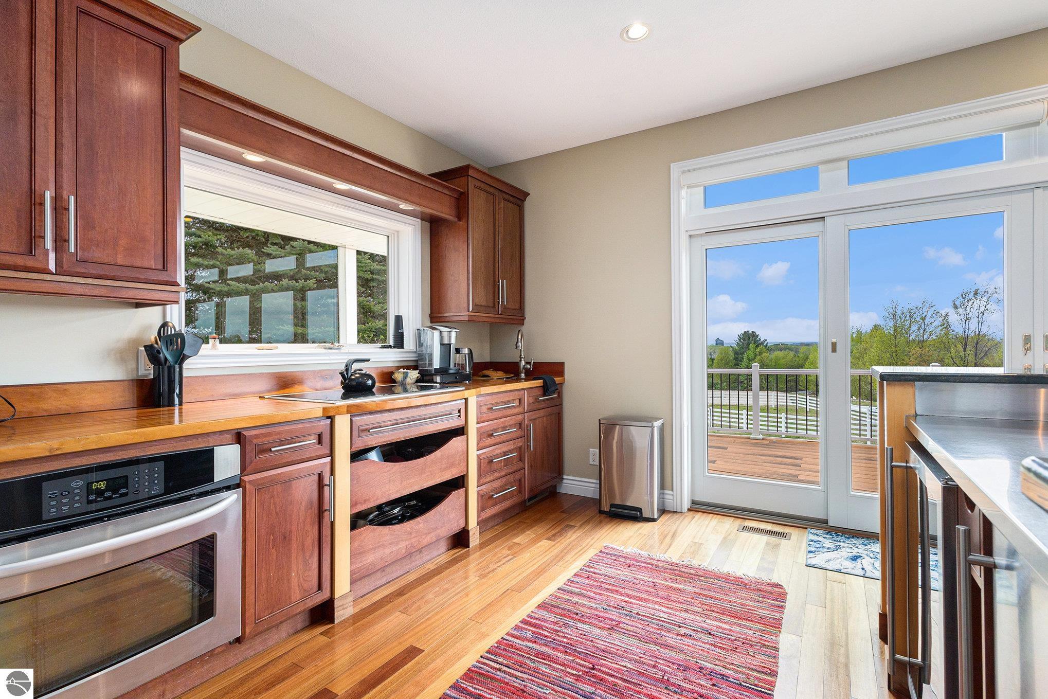 Kitchen with reddish wood cabinetry and countertops, opening through sliding glass doors onto a deck.