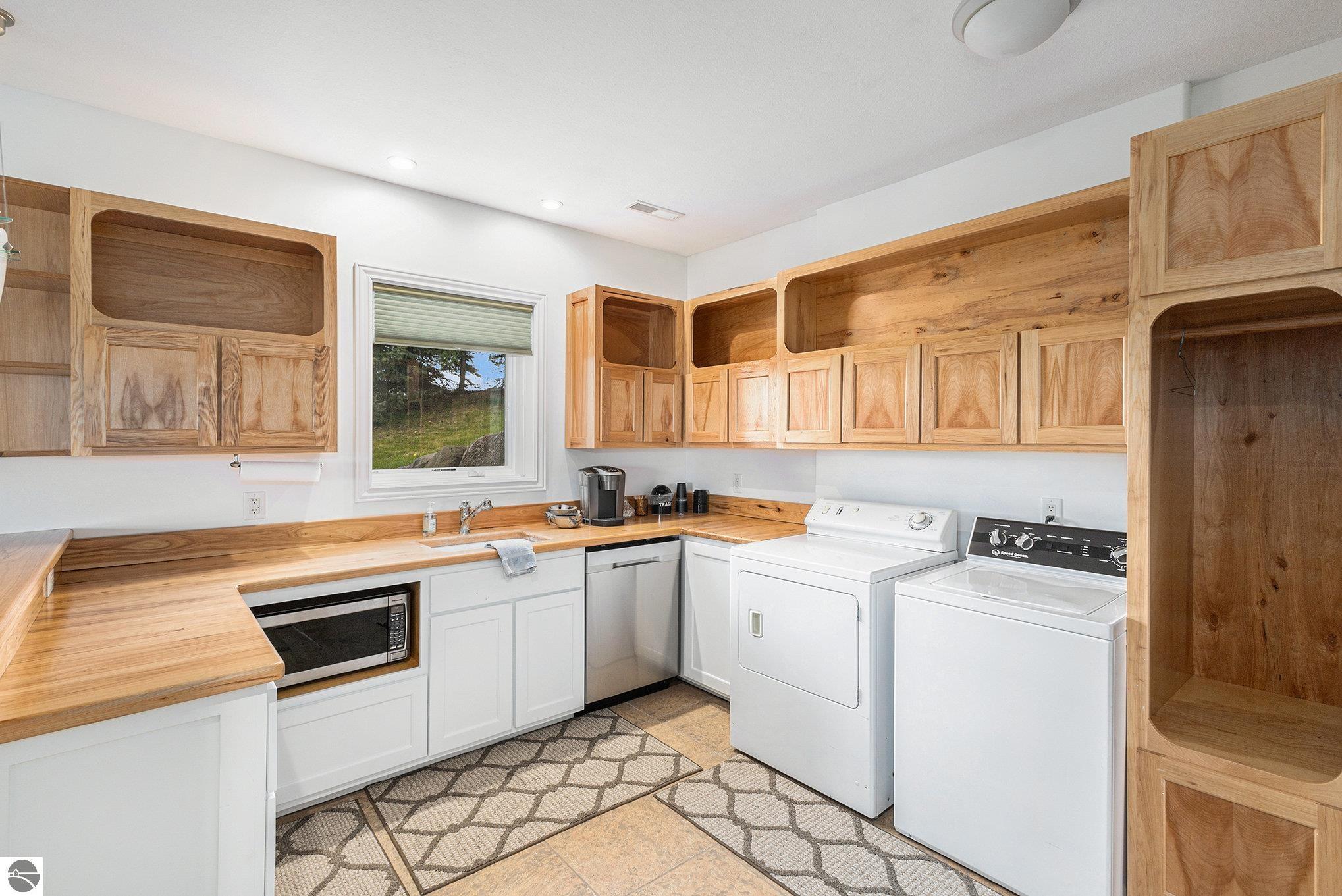 Laundry room with wood cabinetry, a built-in microwave, and white washer and dryer.