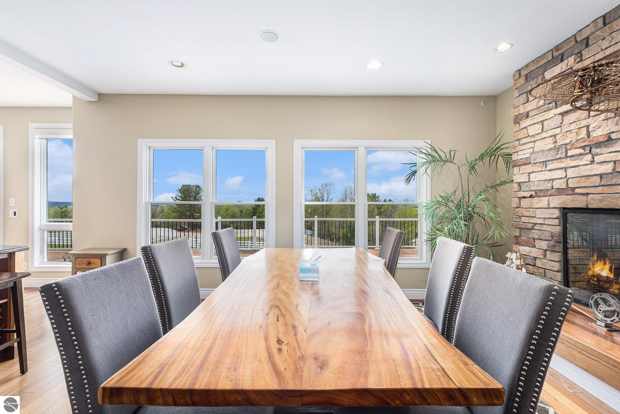 Dining room with a live-edge wood table, large windows, and a stone fireplace.