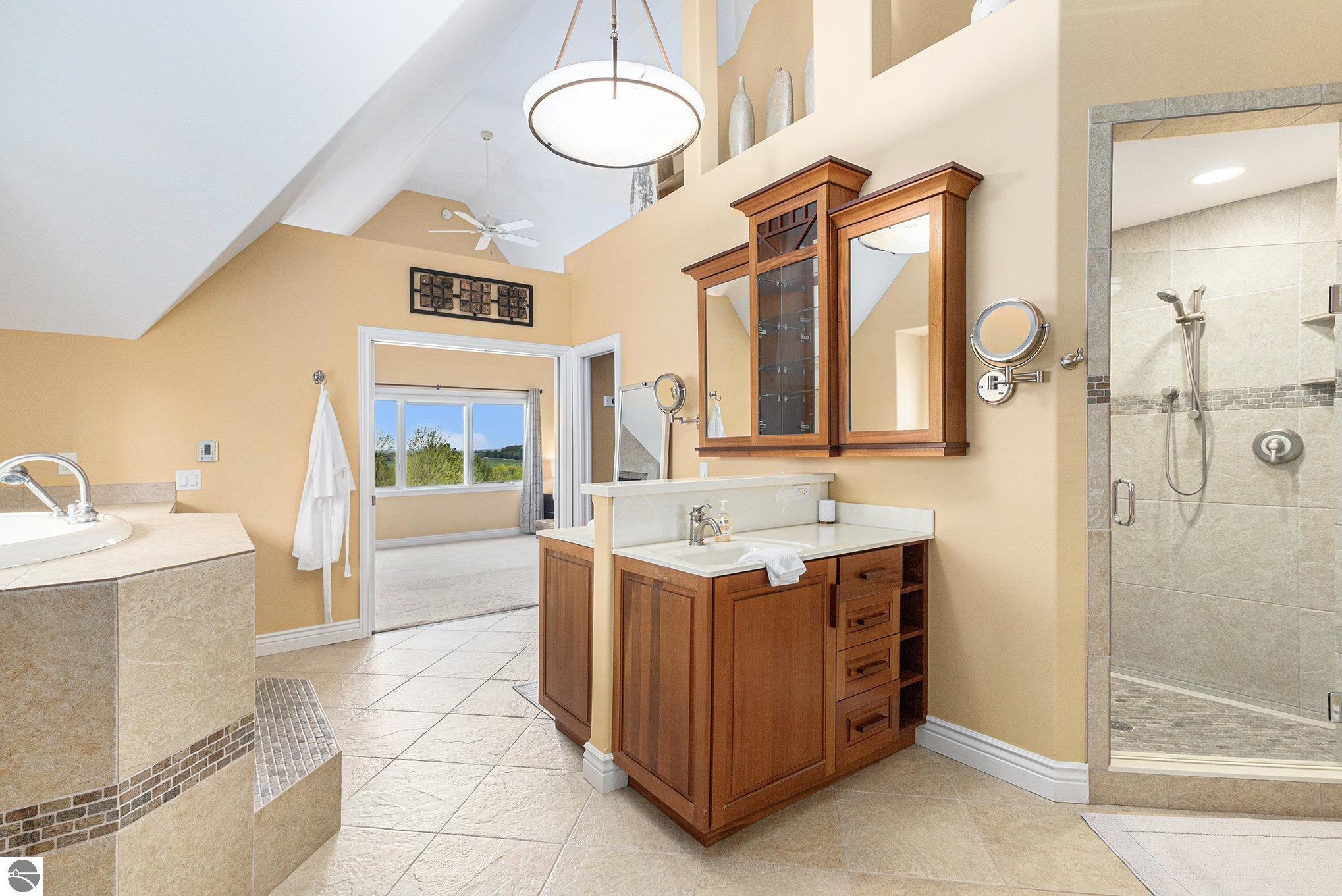 Vaulted bathroom with a wood vanity, tiled walk-in shower, and built-in soaking tub.