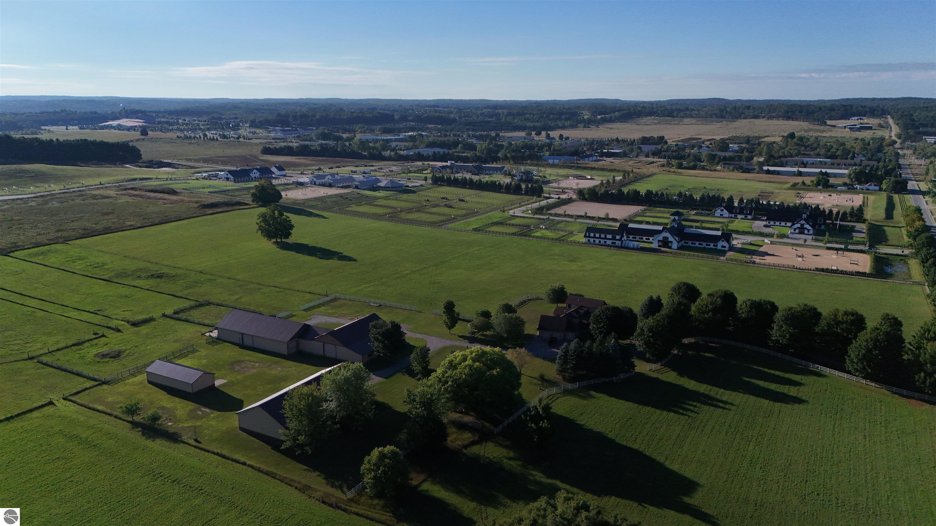 Aerial view of an equestrian property with broad pastures, fenced paddocks, barns, and riding arenas.