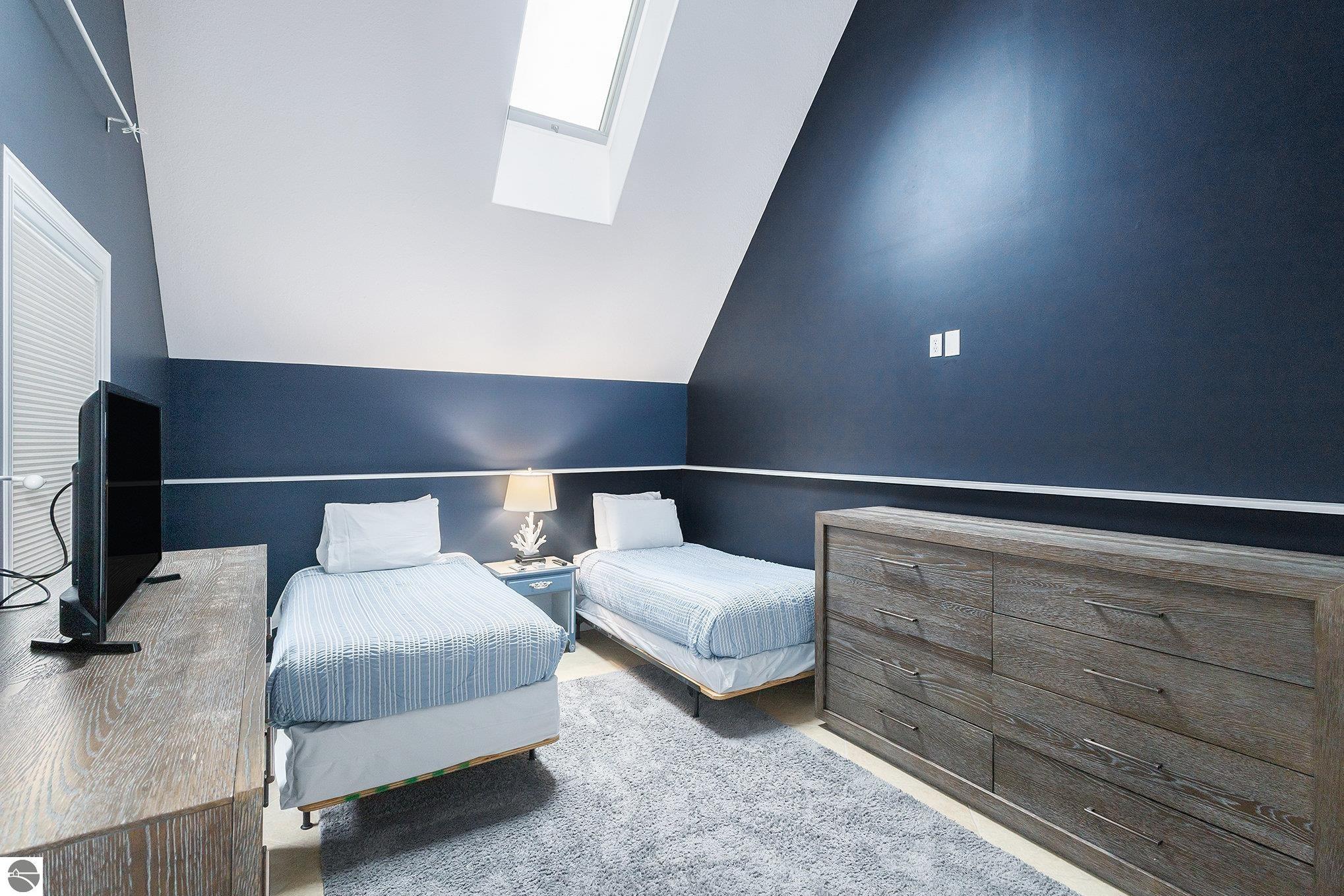 Bedroom with two twin beds, dark blue walls, and a skylight.