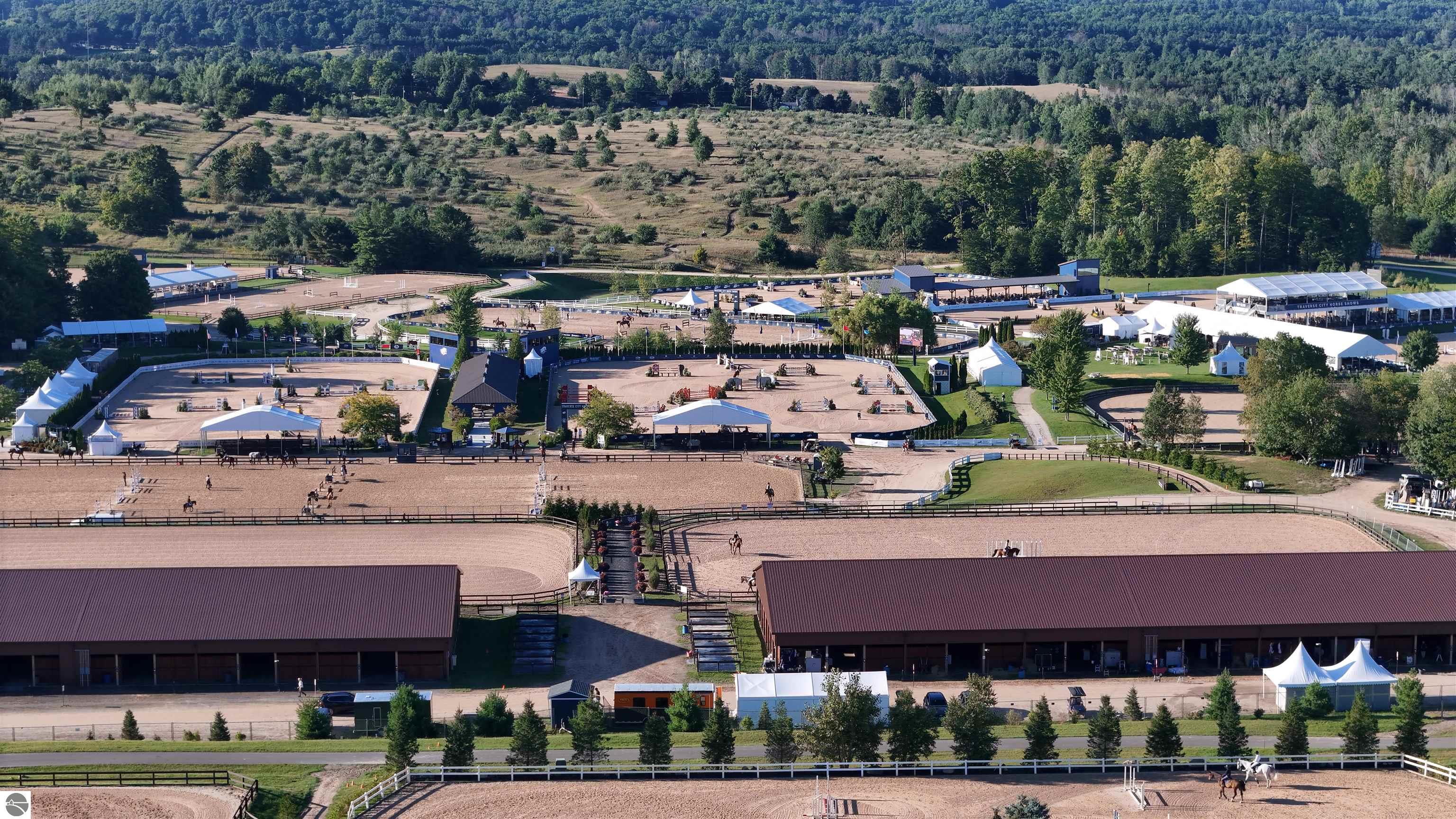 Aerial view of an equestrian facility with multiple riding arenas, barns, and event tents.