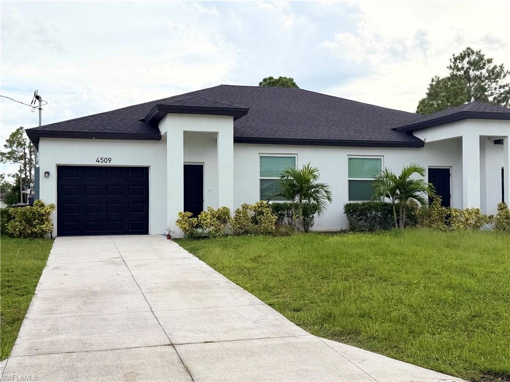 White single-story house with a black garage door, dark roof, and wide concrete driveway.