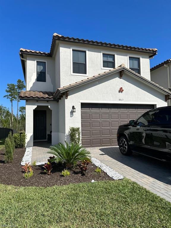 Two-story white stucco home with a tile roof, landscaped front yard, and black SUV in the driveway.