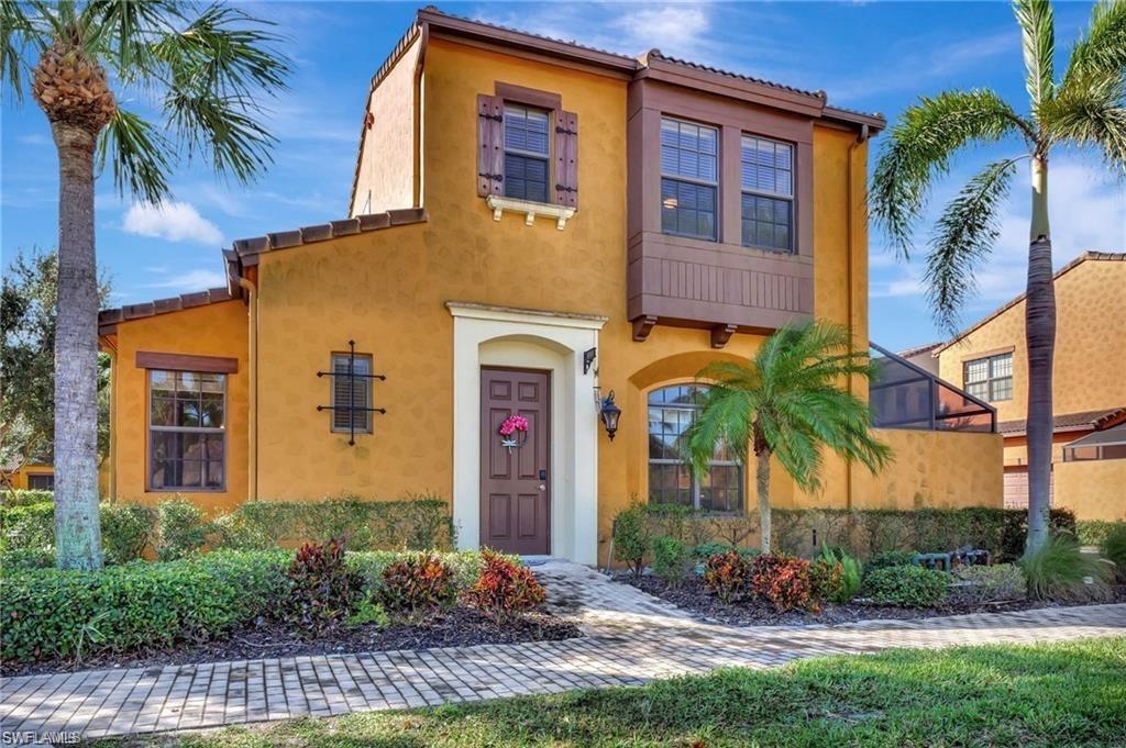 Two-story ochre stucco home with palm trees, a tiled roof, and landscaped front walkway.