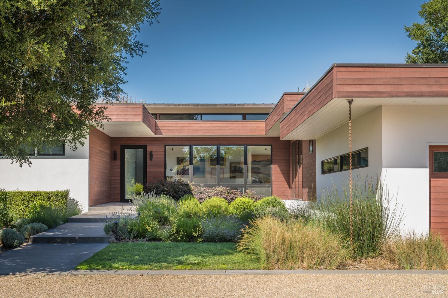 Modern Sonoma home with red wood siding, white stucco, and landscaped entrance.