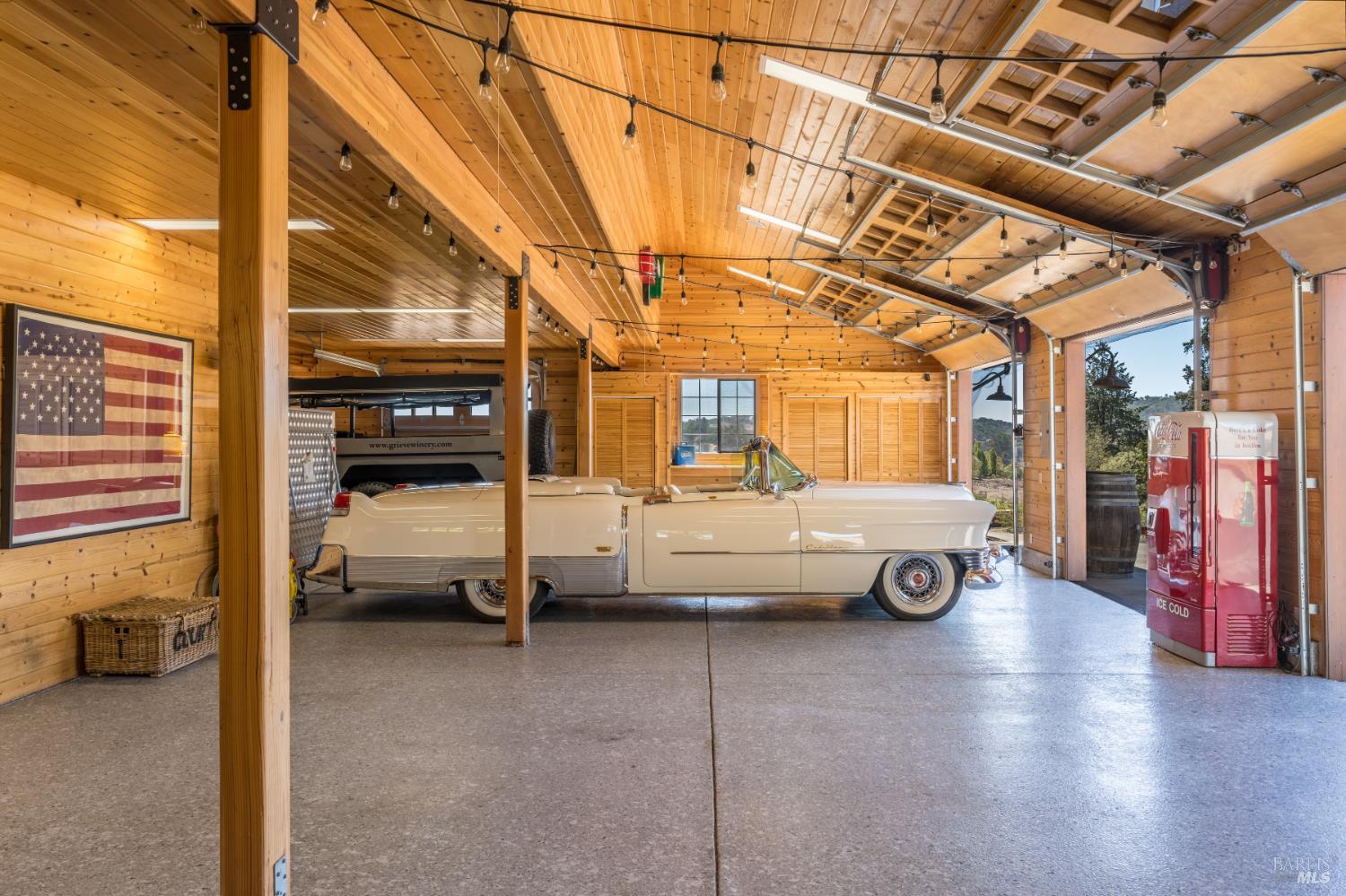 Wood-paneled garage with a cream vintage convertible and red ice cream freezer.