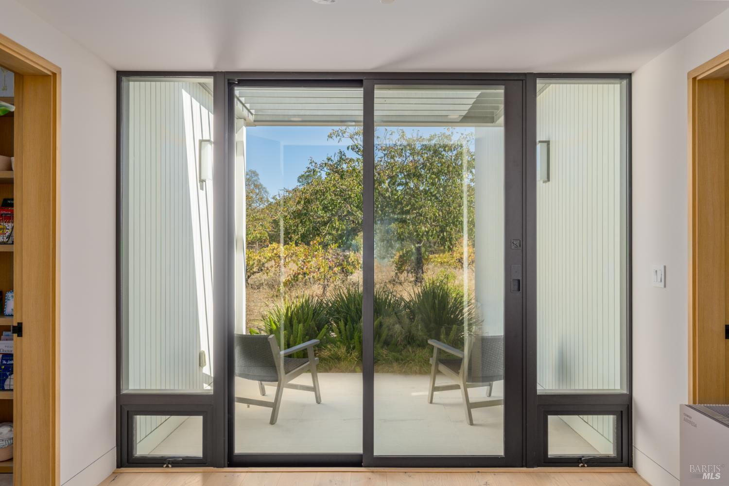 Room with sliding glass doors opening to a covered patio and landscaped garden.