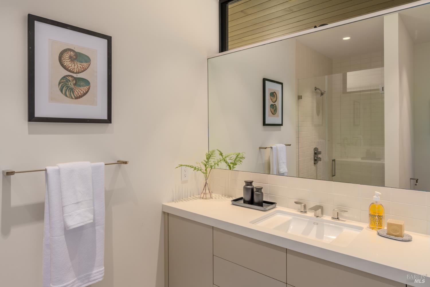 Modern bathroom with a long double-sink vanity and glass-enclosed tiled shower.