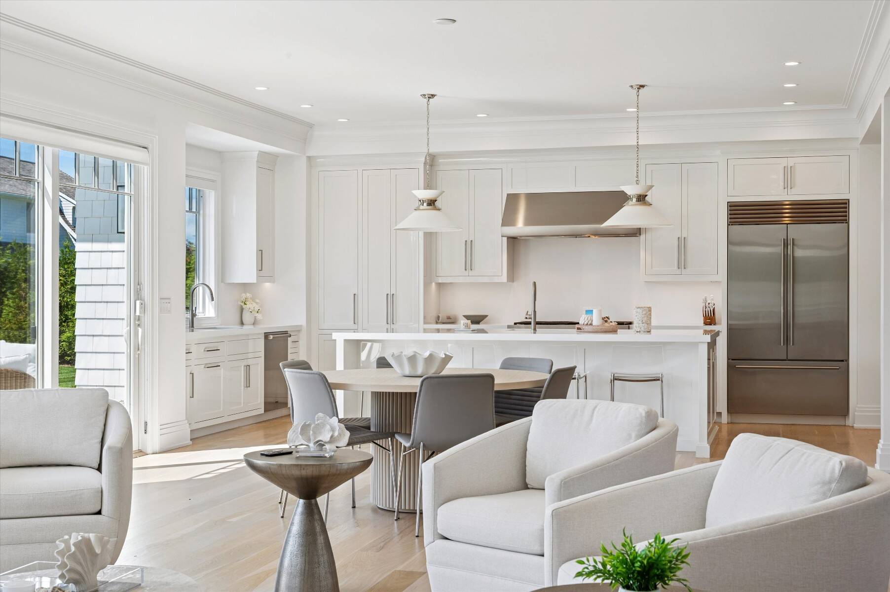 Open-plan kitchen with white cabinetry, a large island, stainless steel appliances, and an adjoining dining and living area.