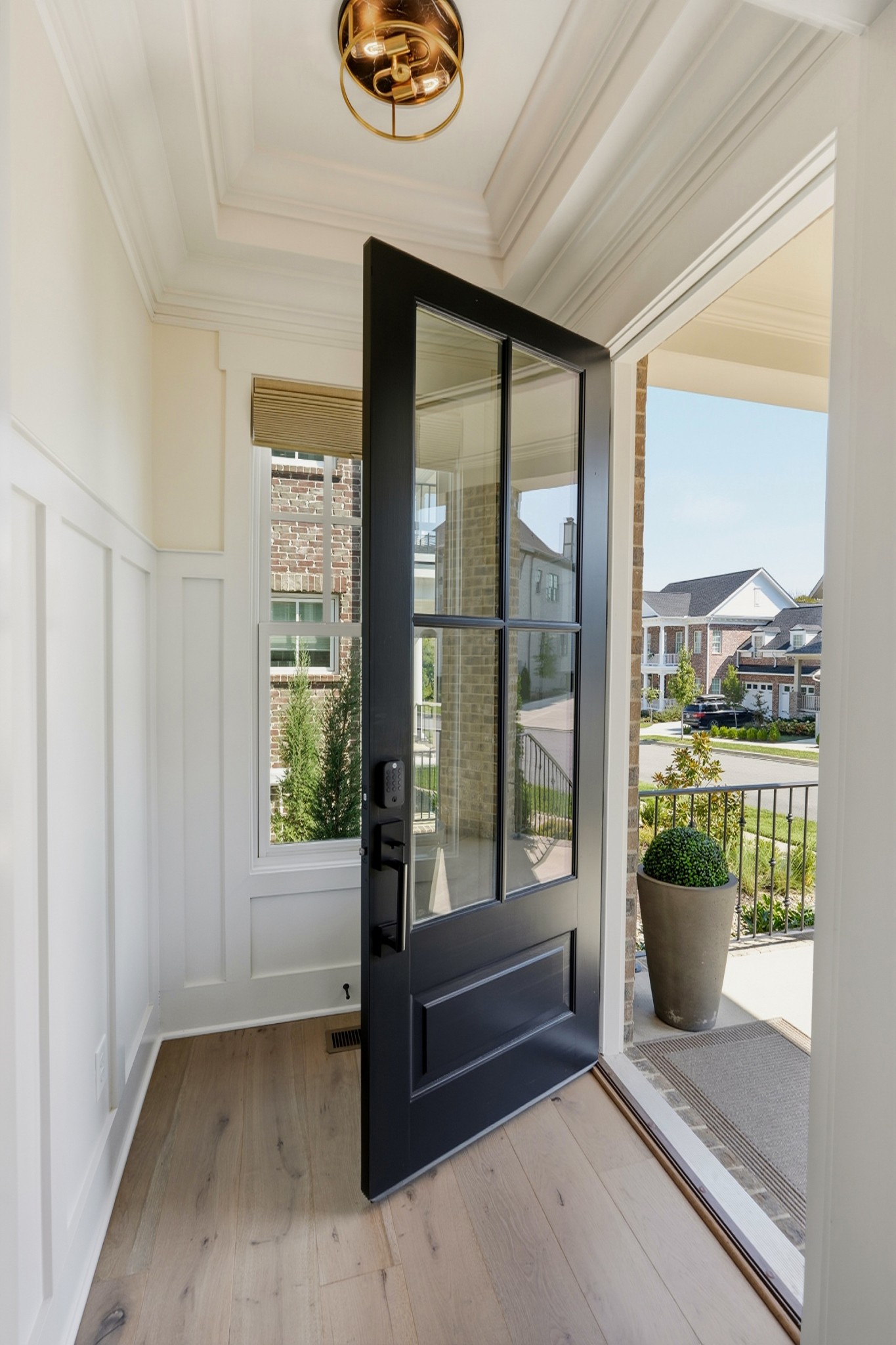 Entryway with open black glass front door and view of the sunny front porch.