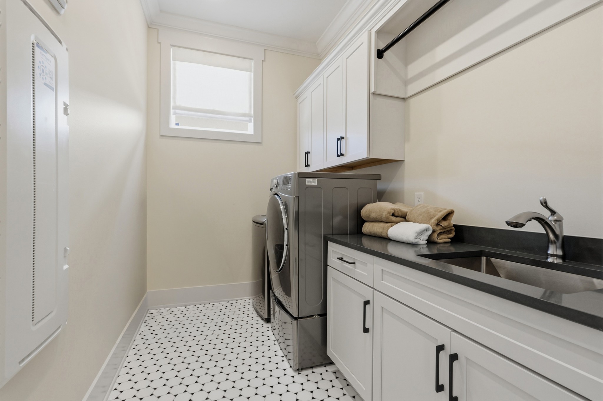 Laundry room with washer and dryer, white cabinets, a dark sink counter, and patterned tile floor.