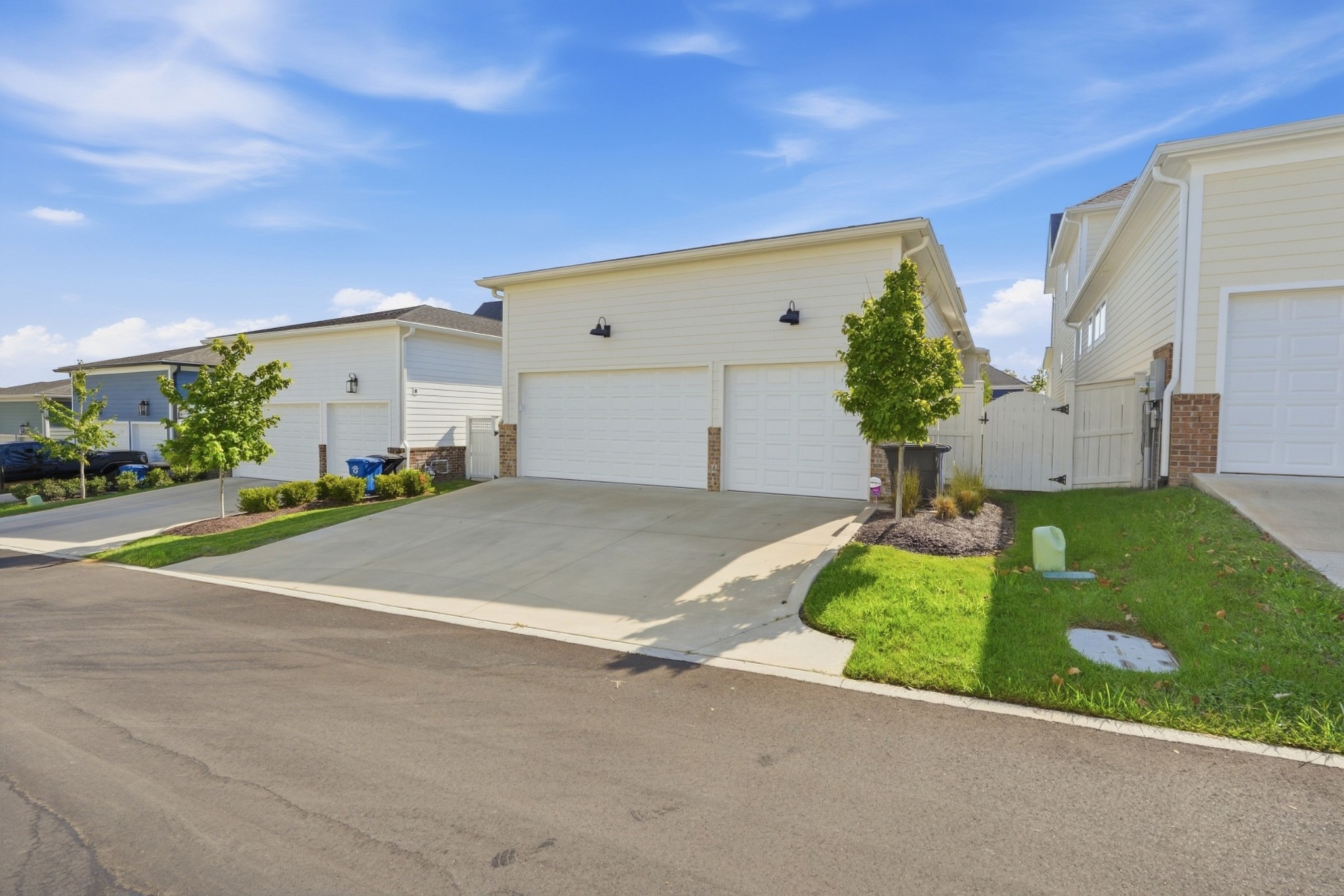 Light-colored house with two garage doors and a wide concrete driveway.