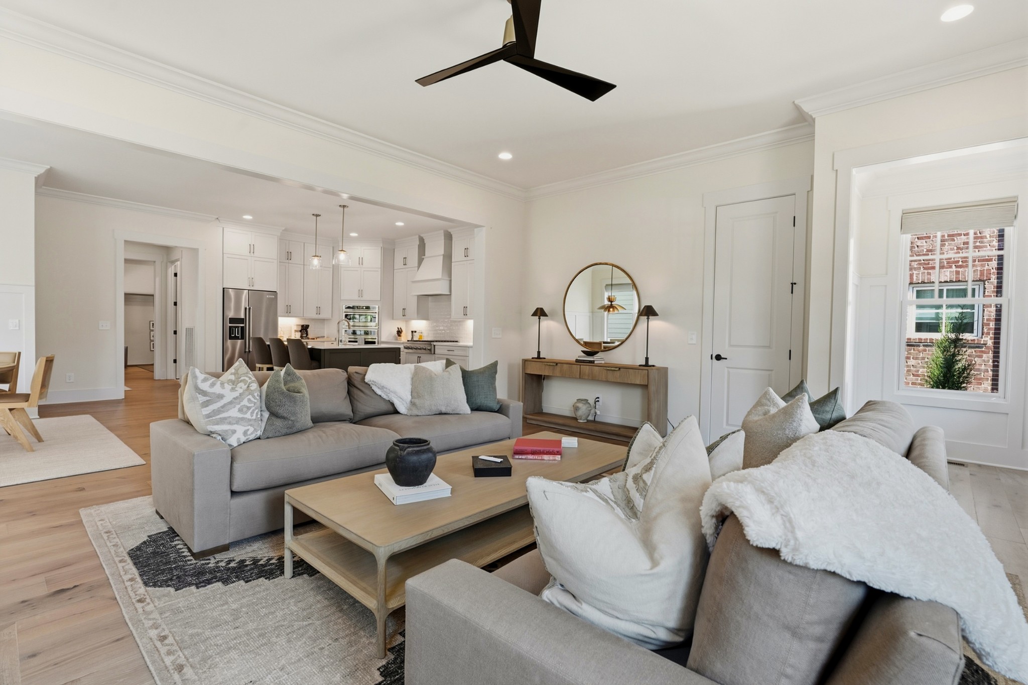 Staged living room with gray sofas, a wood coffee table, and an open white kitchen.