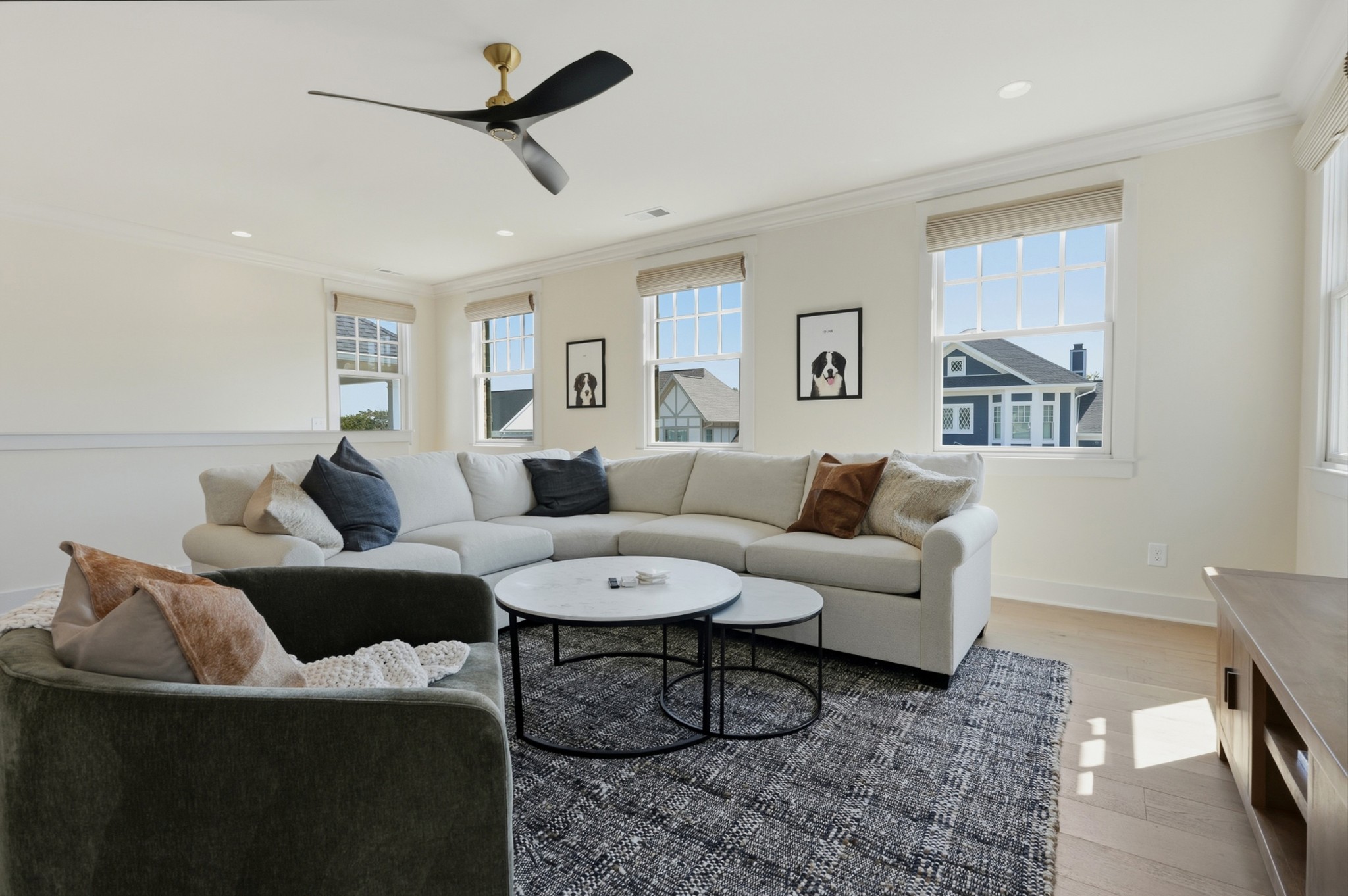 Bright living room with a large sectional, nested coffee tables, and tall windows.