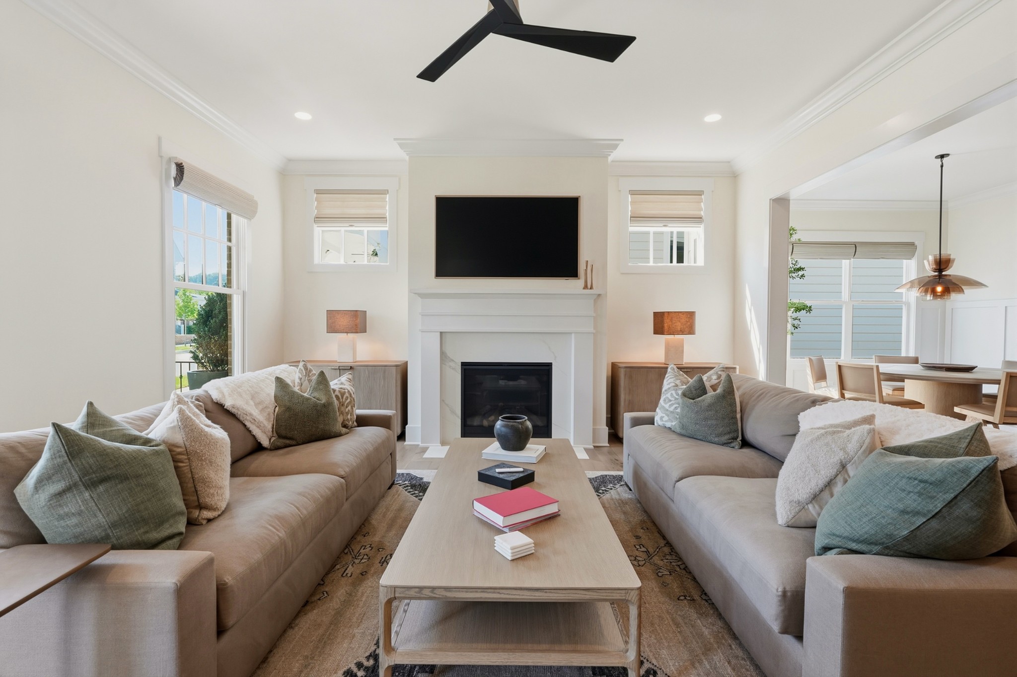 Living room with twin sofas facing a fireplace and TV, opening to the dining area.